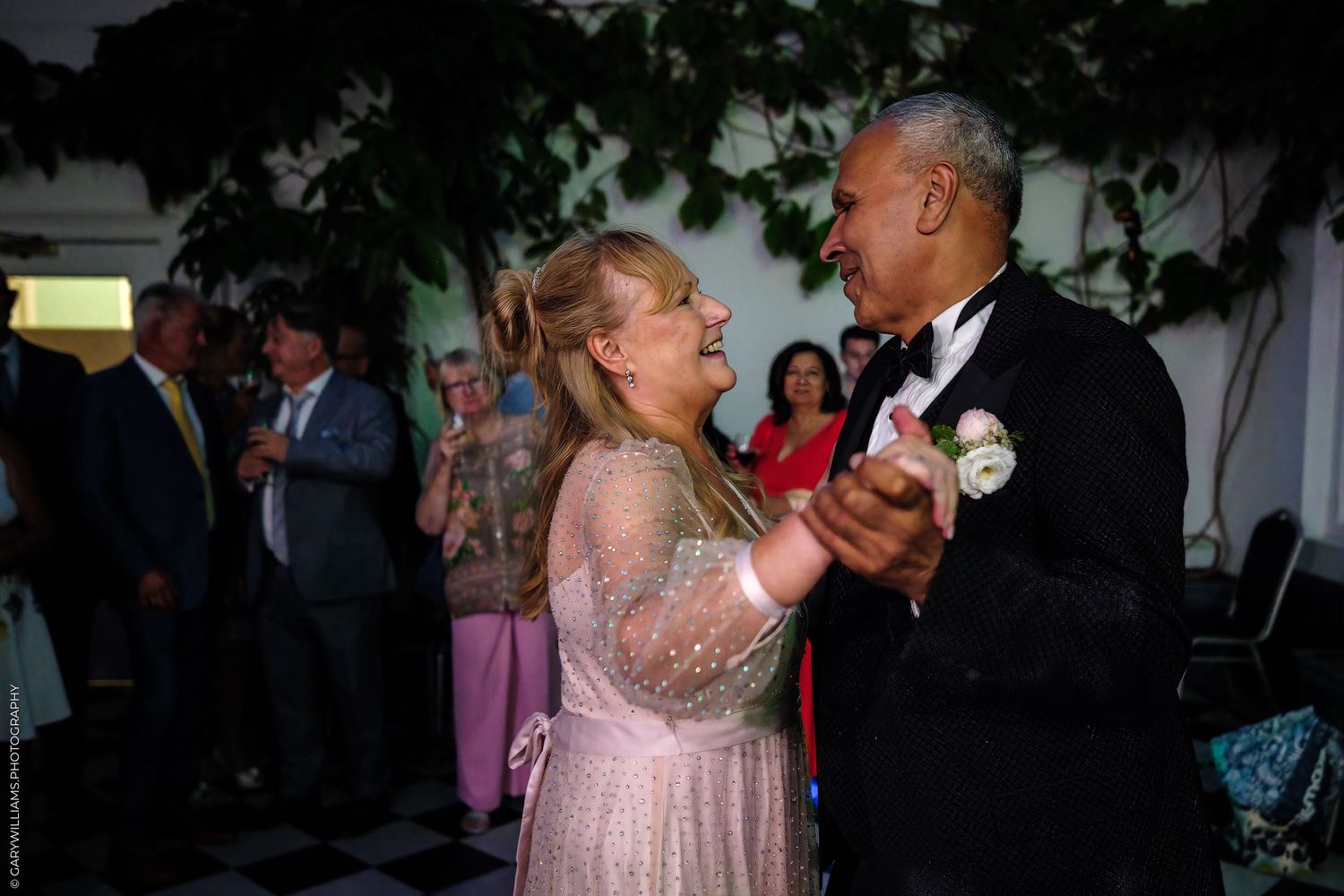 Couple dancing together at an elegant event wearing formal attire in a ballroom setting.
