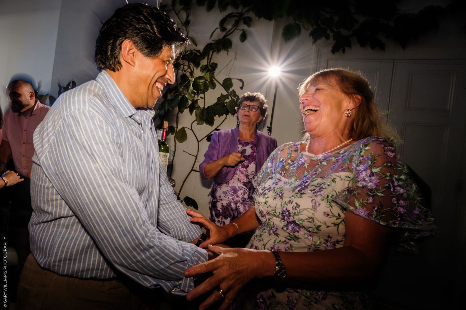 People dancing together in a dimly lit room with smiling faces and joyful expressions.