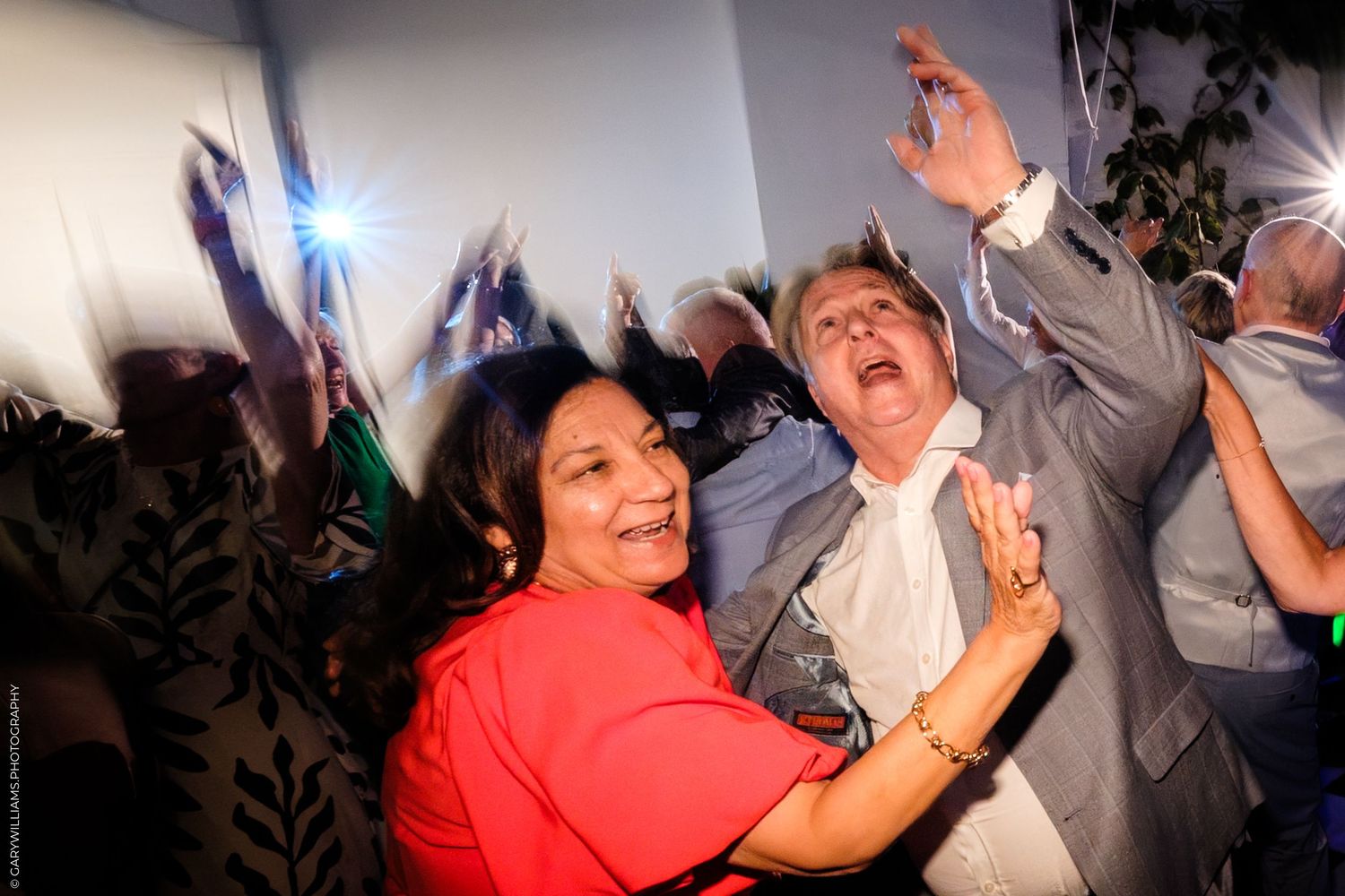 People dancing and having fun at a lively party or celebration event with colorful lighting and festive atmosphere.