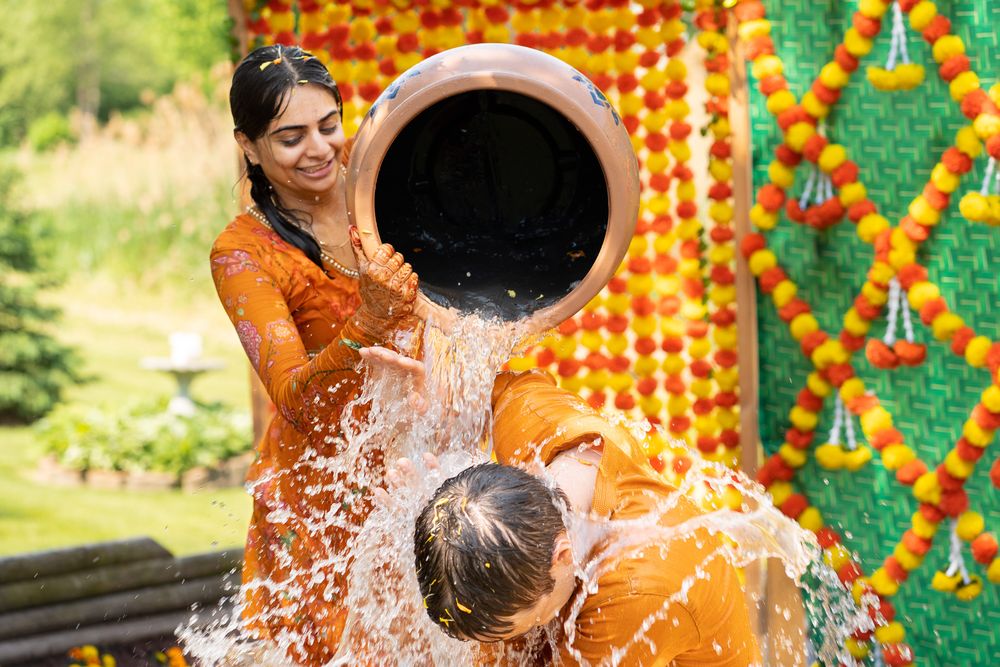 Indian wedding celebration with dancing and colorful marigold flower decorations at outdoor venue. Haldi Quad Cities Photography