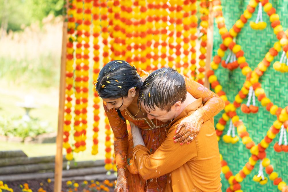 Festive outdoor setting with marigold and green garland decorations hanging against a bright backdrop. Haldi Quad Cities Photography