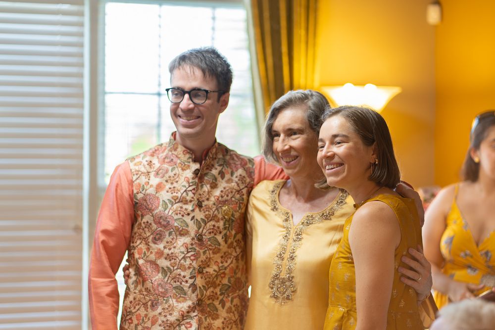 Candid moments captured during an Indian celebration with people wearing yellow and floral outfits indoors. Haldi Quad Cities Photography
