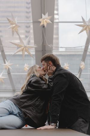 A romantic couple sharing intimate moments on a couch beneath hanging star decorations in a softly lit room.