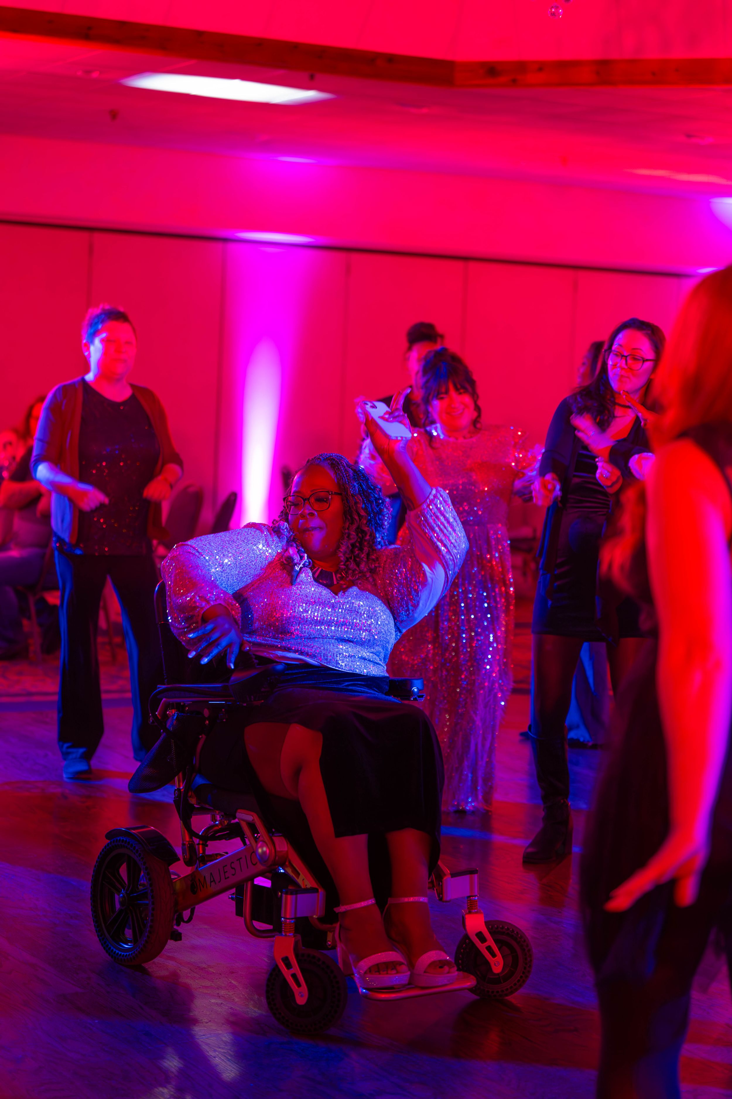 Dancing figures silhouetted against vibrant pink and purple lighting at a party or dance venue create a lively atmosphere. Quad Cities Photo
