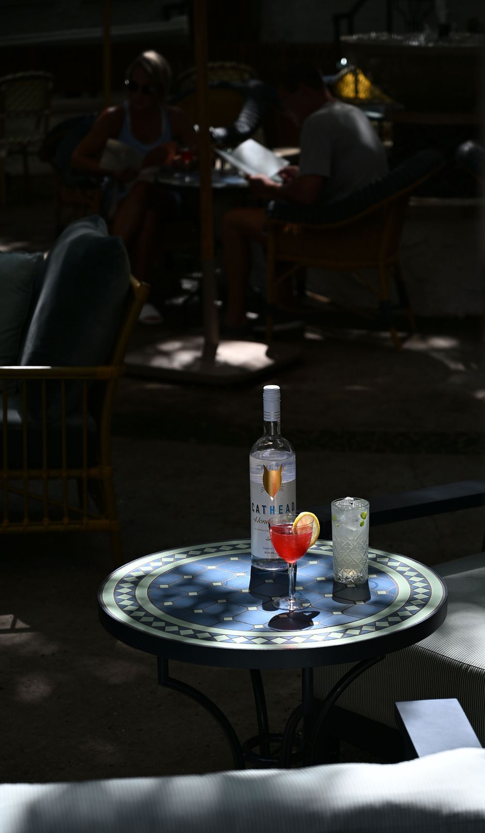 A sequence of cocktail drinks and glasses on round tables in dim lighting conditions.