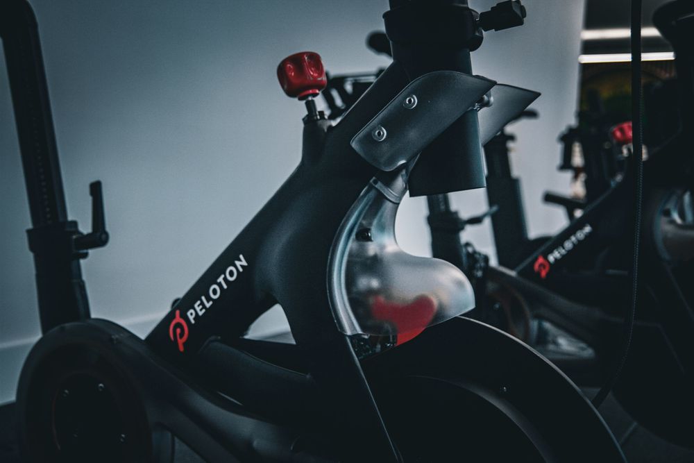 Close-up view of a black Peloton exercise bike frame with red accents against a dark background.