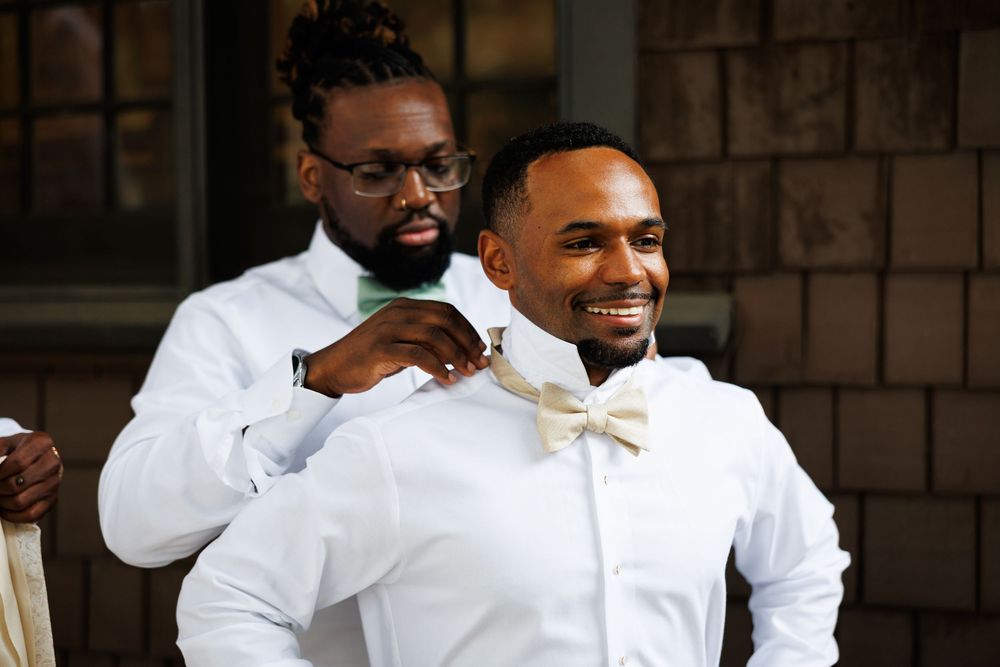 Wedding party members in white suits share joyful laughter during a special celebration moment.
