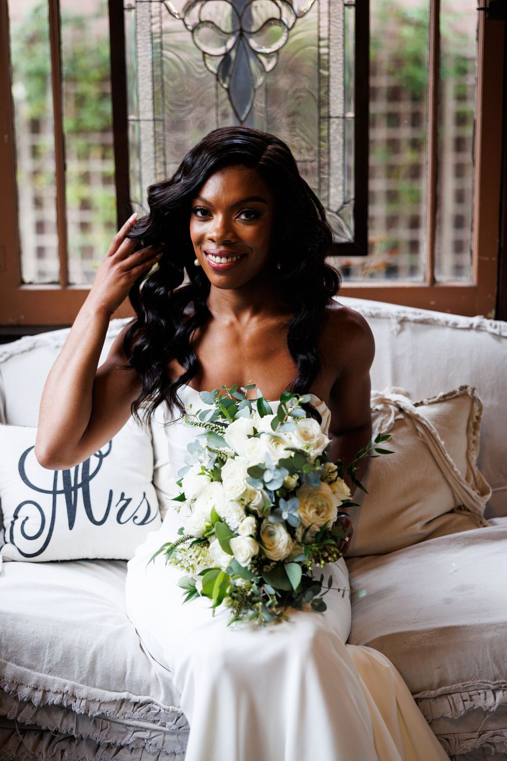 Beautiful wedding portrait on white couch with elegant bridal bouquet at the Chapel of Orange in Orange County, California.