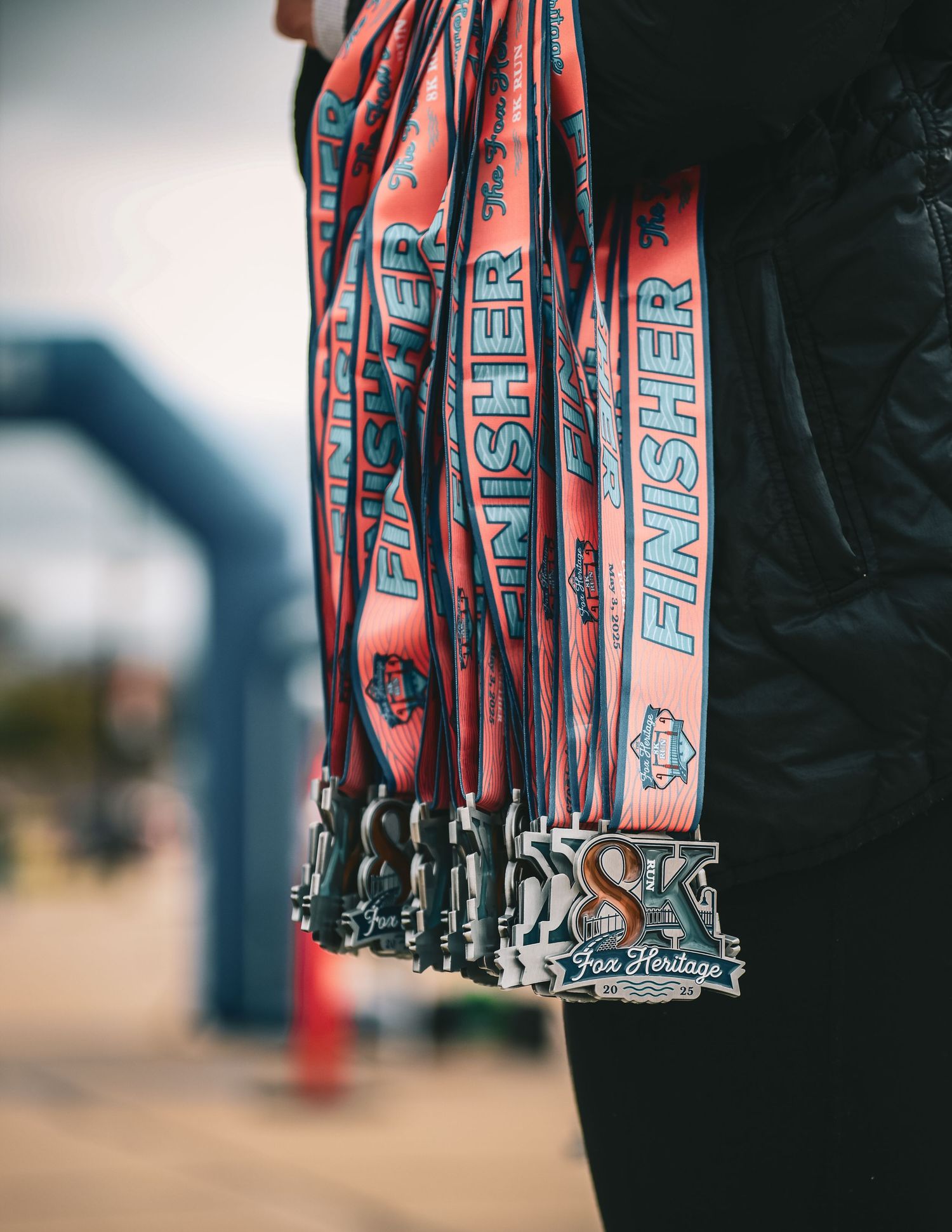 A collection of red and blue medal lanyards with the text 'FINISHER' hanging together in a close-up view.