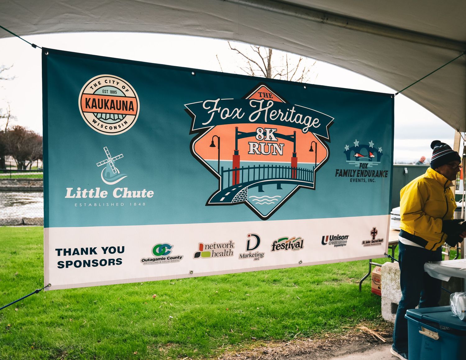 A curved wall displays colorful sponsor logos and branding for a sports event or fitness competition.