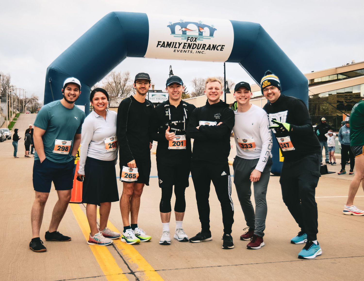 Athletes gathering near a blue inflatable arch at a family fitness race event.