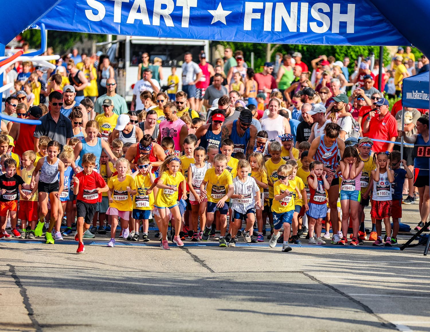 Large group of marathon runners at the starting line beneath a blue Start/Finish banner during a race event.