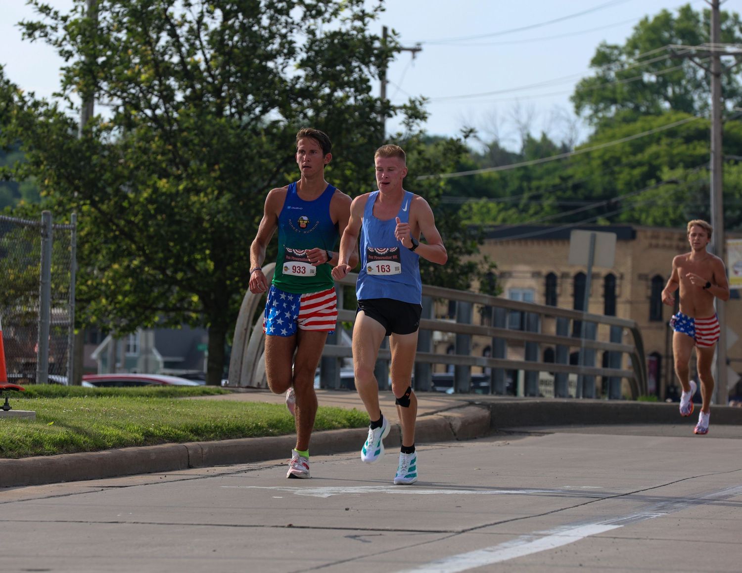 Runners racing along a street during a competitive marathon event on a sunny summer day.