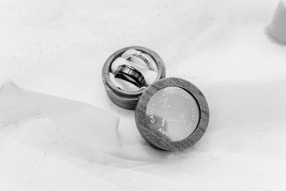 A black and white photo of two makeup compacts or cosmetic containers with round metal and glass design.