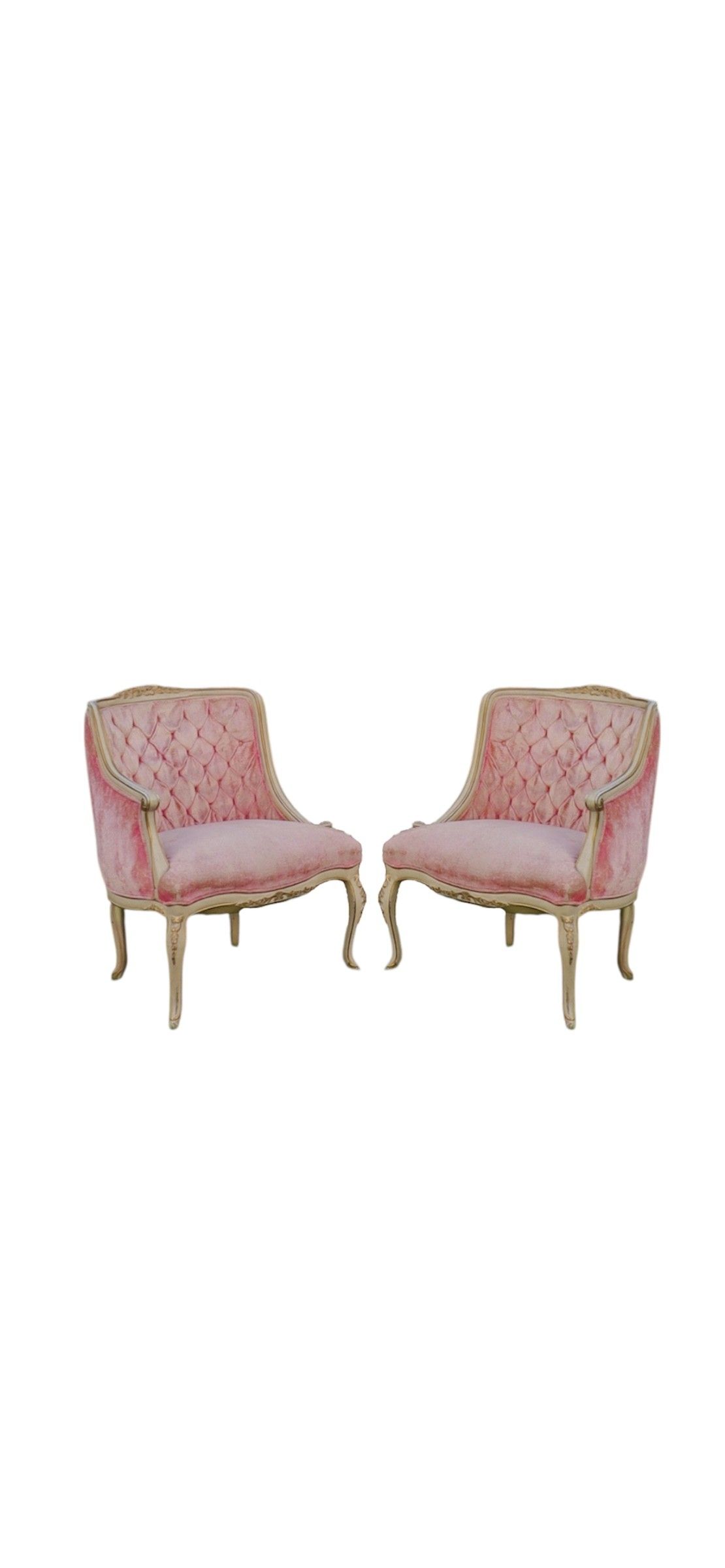 Two vintage pink velvet chairs with tufted upholstery and white painted frames sit on grass against green foliage.