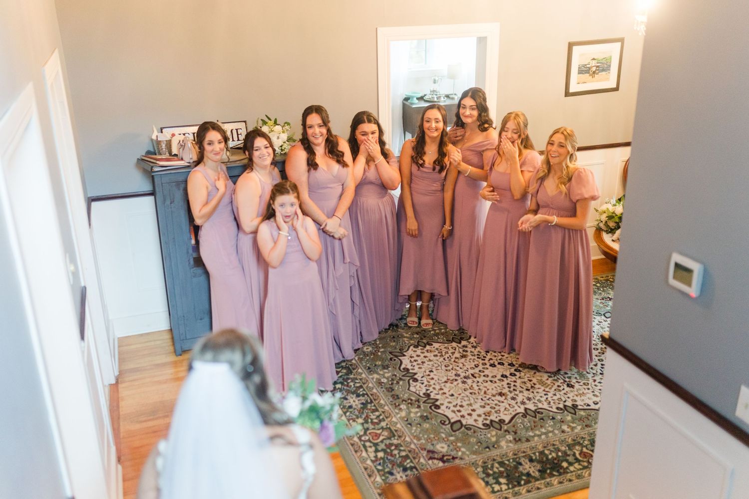 Bridesmaids in matching purple and pink dresses stand together in elegant poses at a formal wedding event.