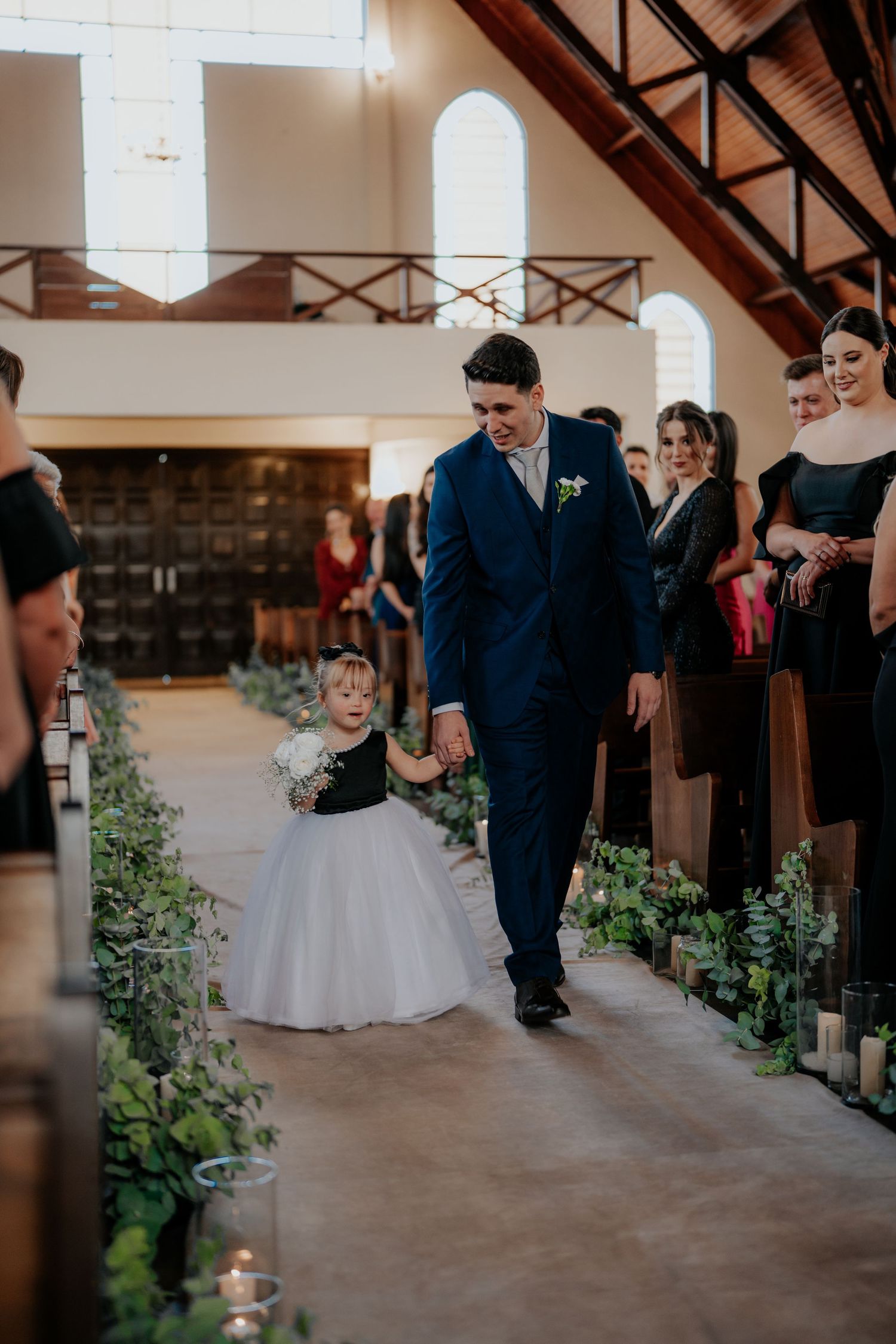 Wedding ceremony venue with rustic exposed beams and green aisle decorations.