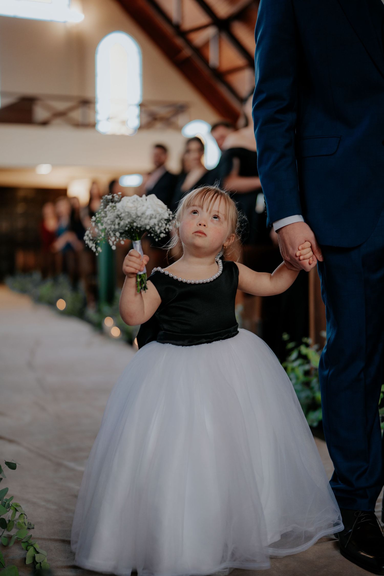 Young flower girls in white tulle dresses walk down the wedding aisle.