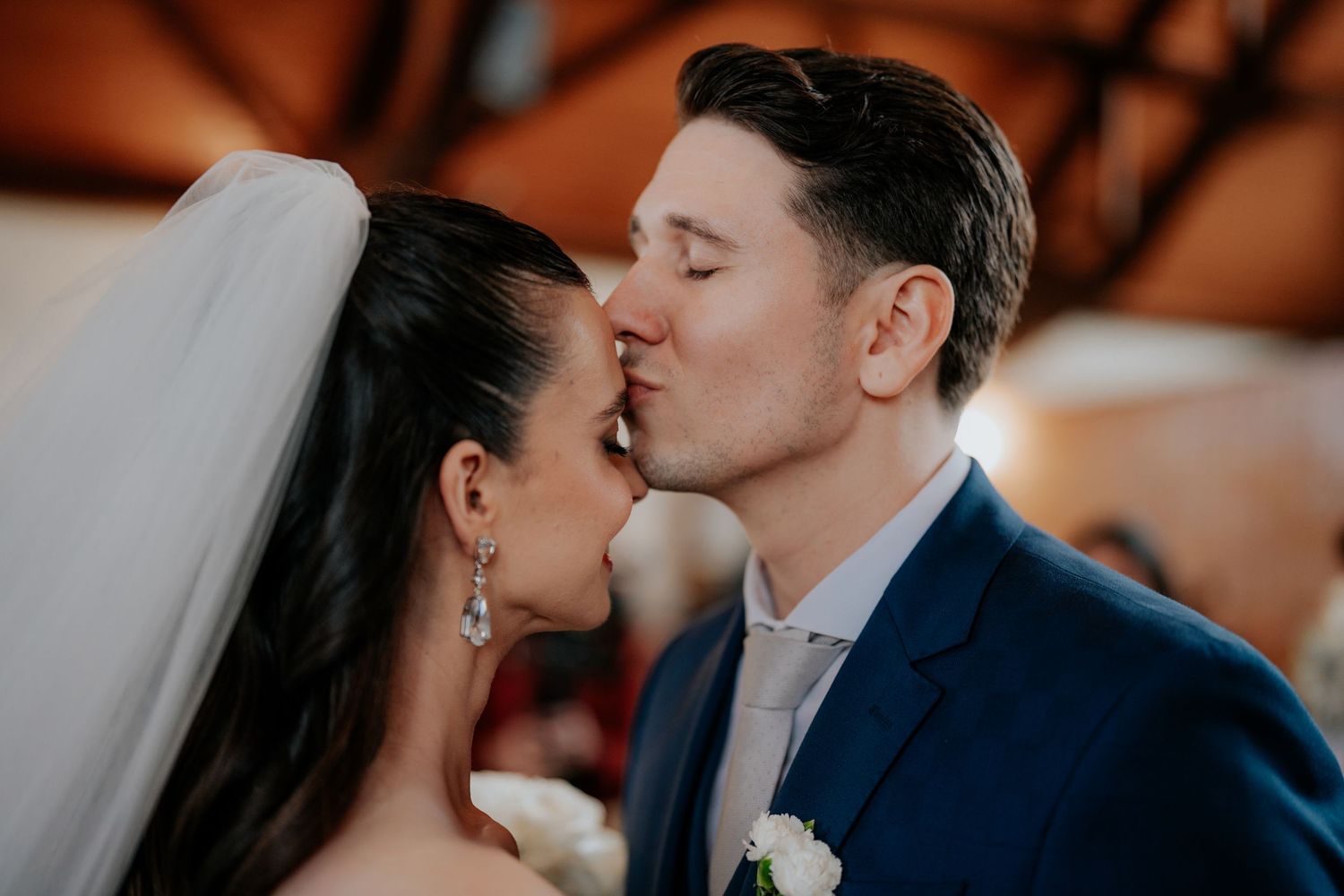 Romantic wedding ceremony moment in dimly lit indoor venue.
