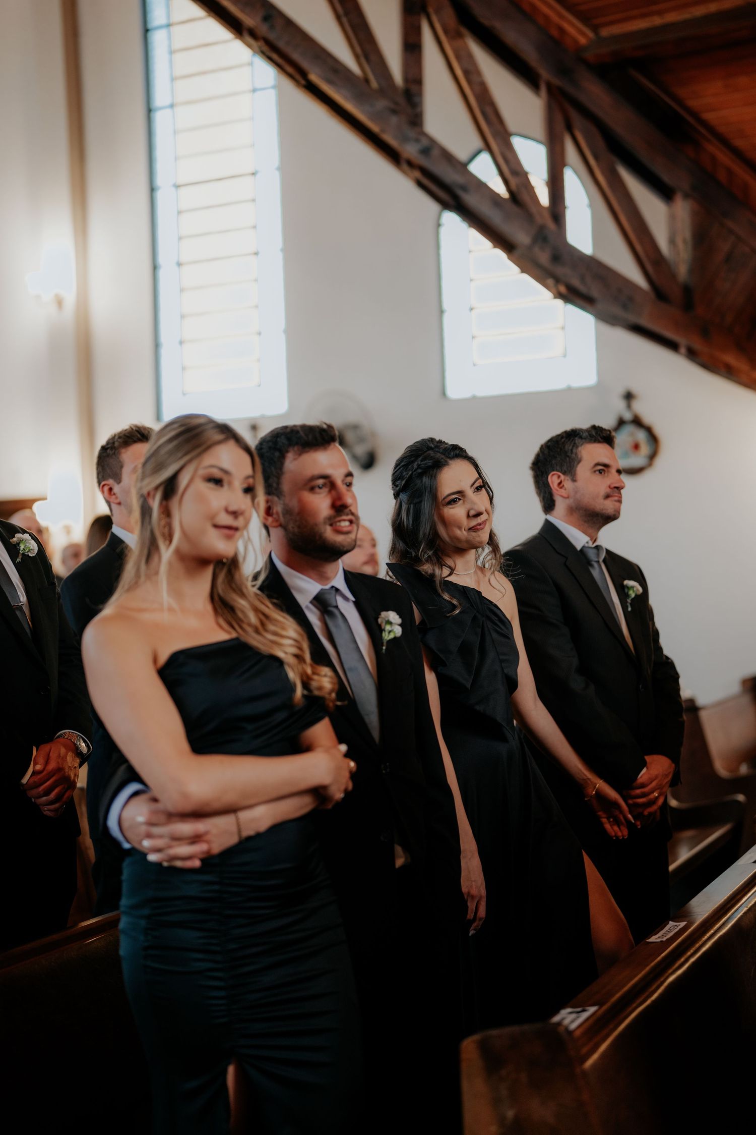 Wedding guests watching the ceremony inside a church with exposed wooden beams.