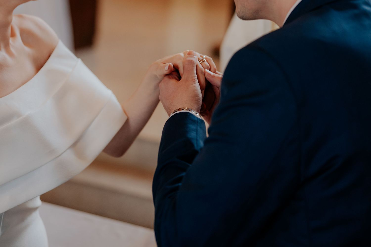 Close-up detail of hands exchanging rings during a wedding ceremony.