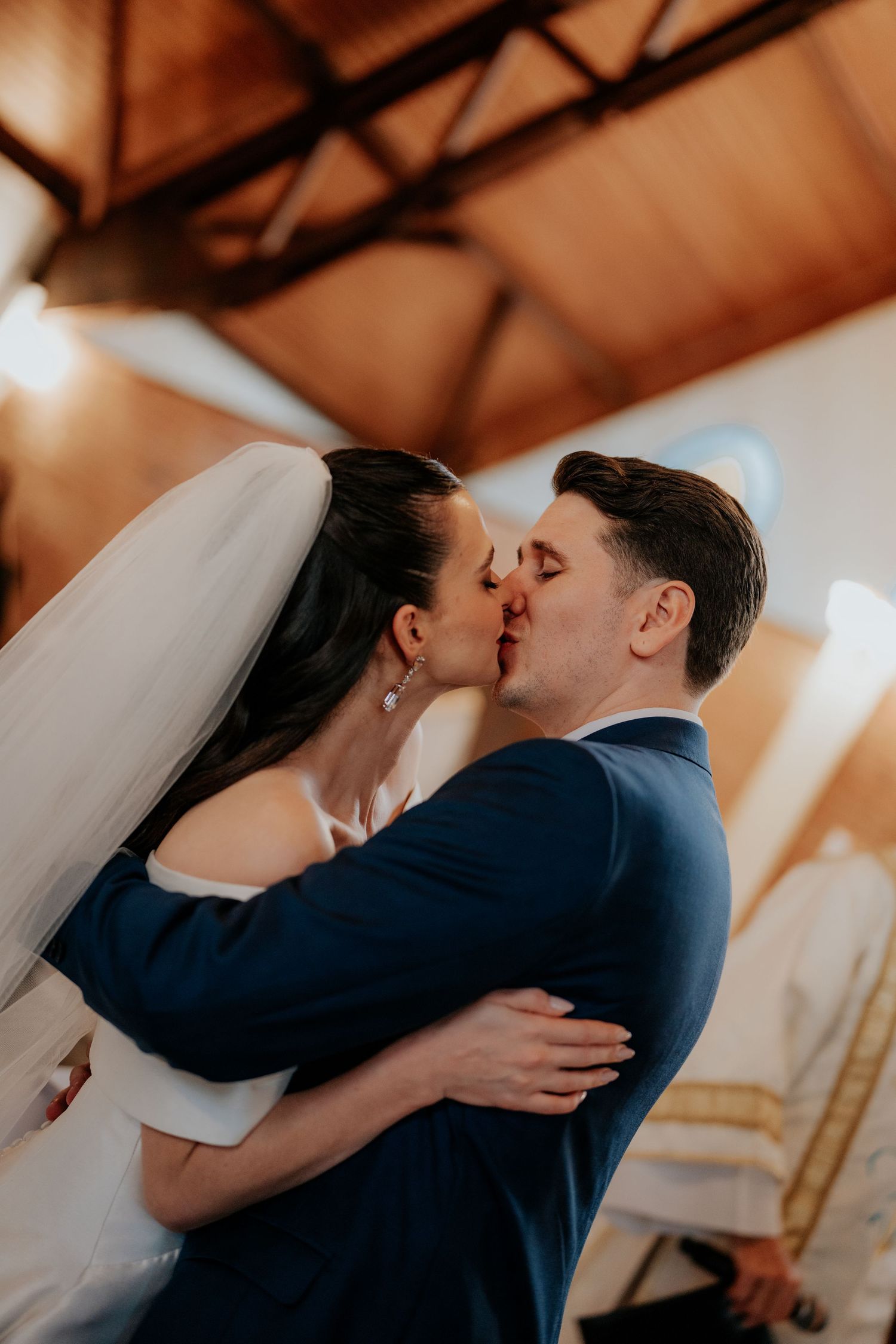 Newlyweds sharing their first kiss during their wedding ceremony in a church.