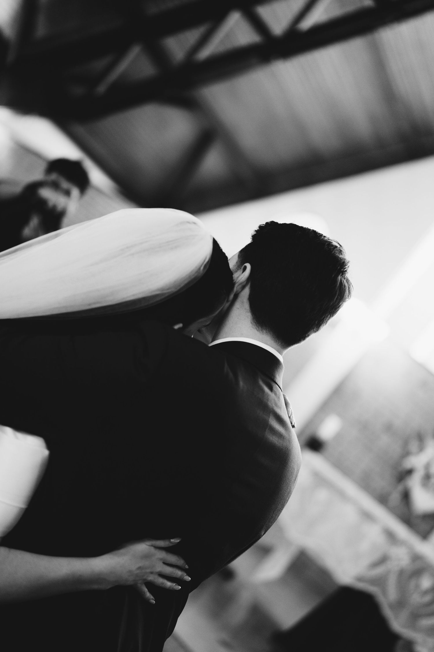 Black and white photo of a couple embracing during their first dance at a wedding reception.