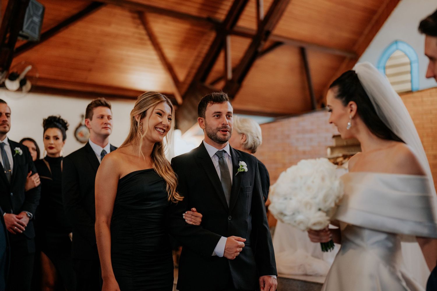 Wedding guests gathered in a rustic wooden chapel watching the ceremony unfold.