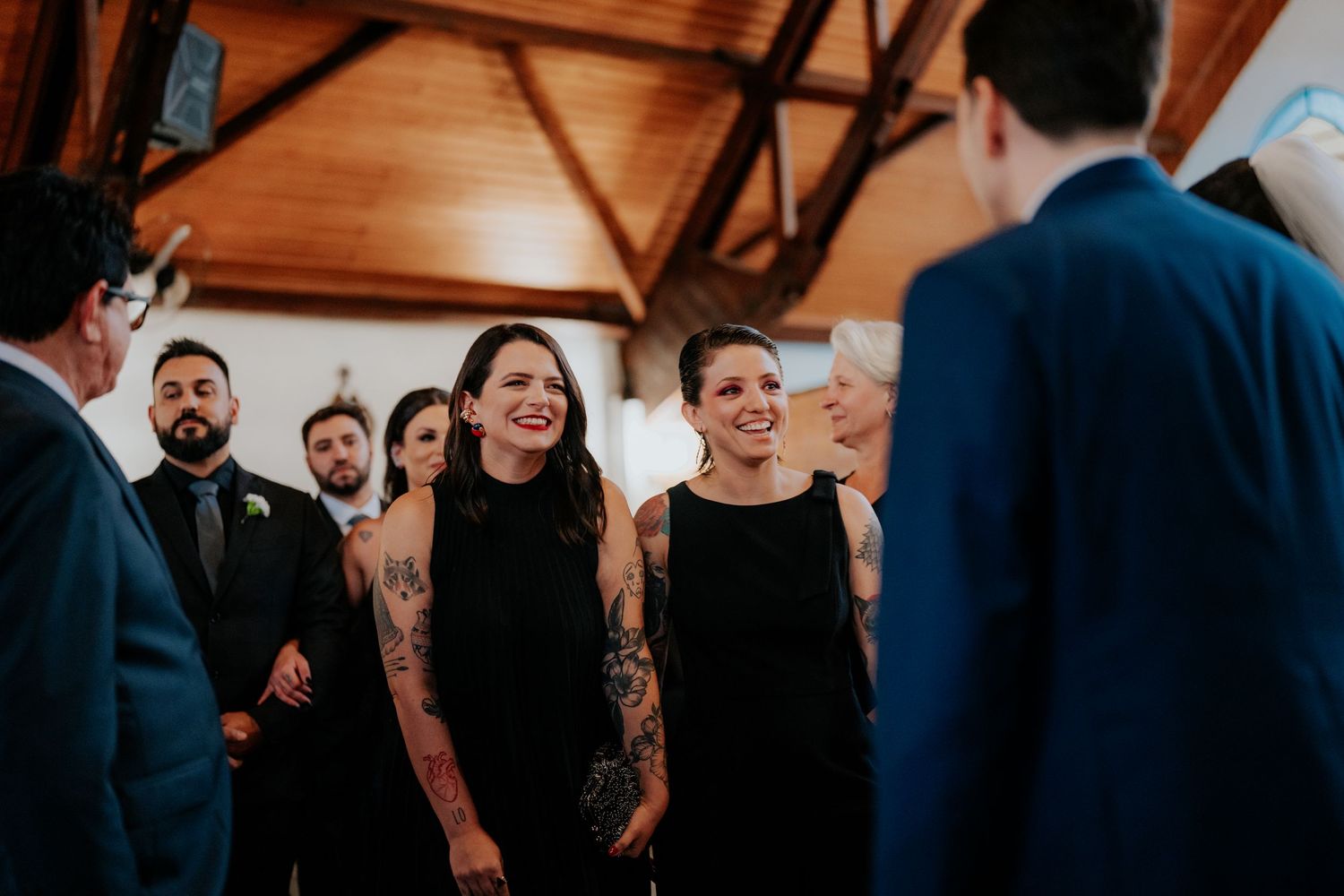 Wedding guests in formal attire share joyful laughter during the ceremony.