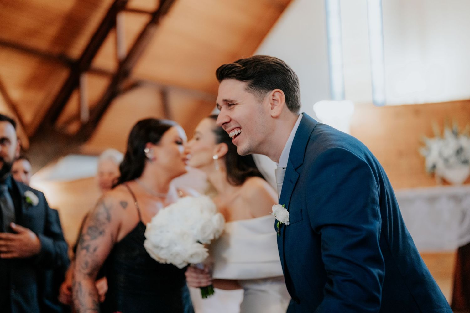 Candid moment of laughter and celebration during a wedding ceremony in a wooden chapel.