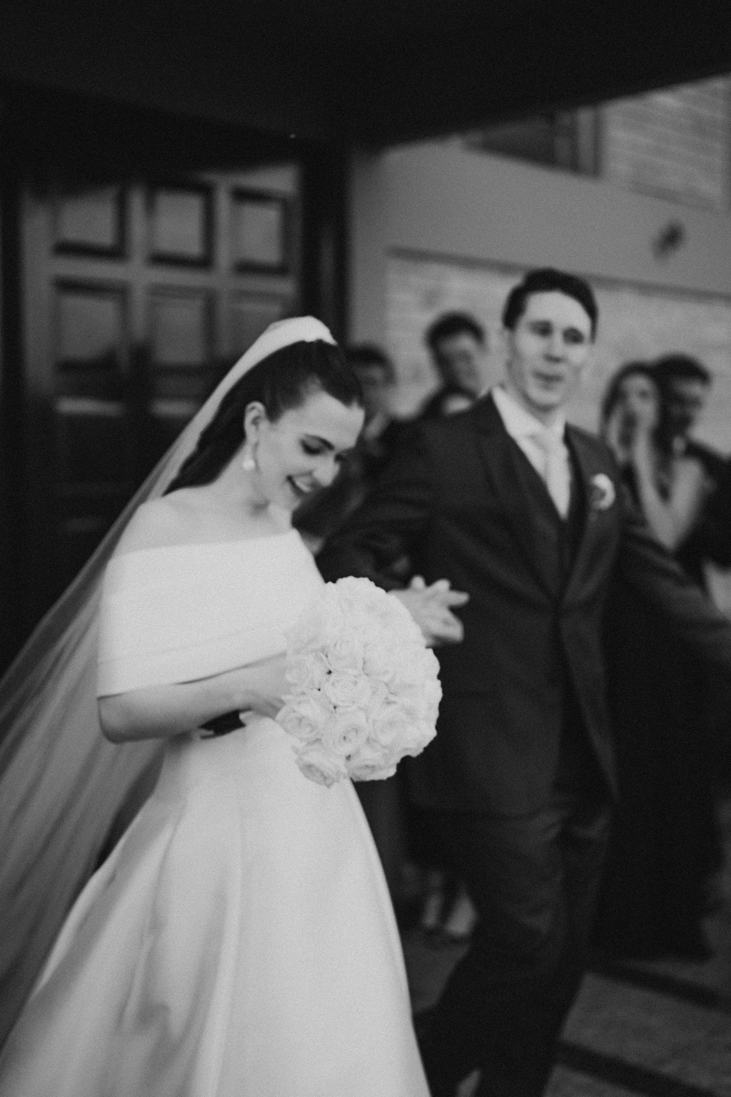 Black and white photo capturing a tender moment with white bouquet at a wedding ceremony.