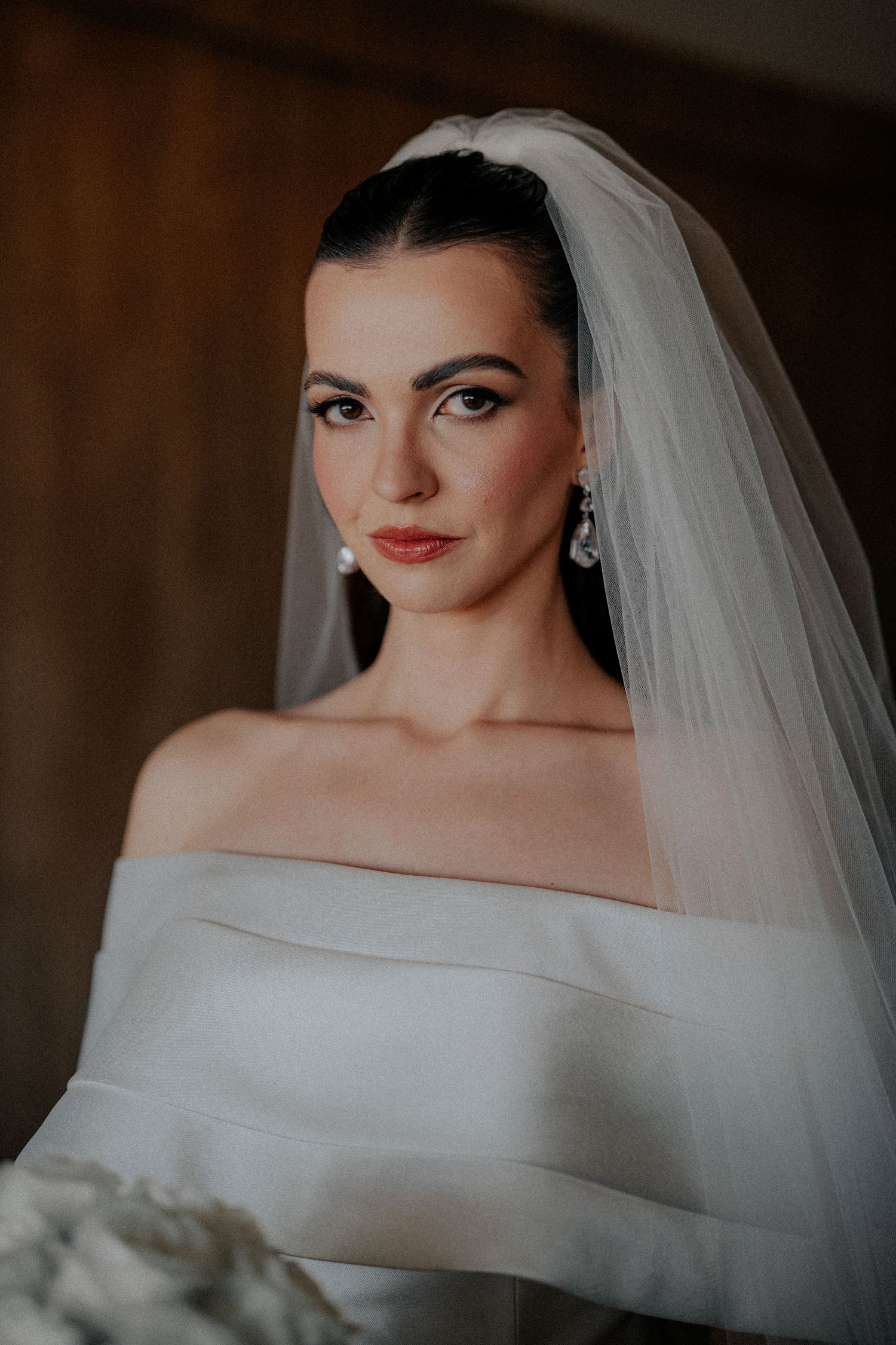 Classic bridal portrait featuring elegant off-shoulder gown and flowing veil.