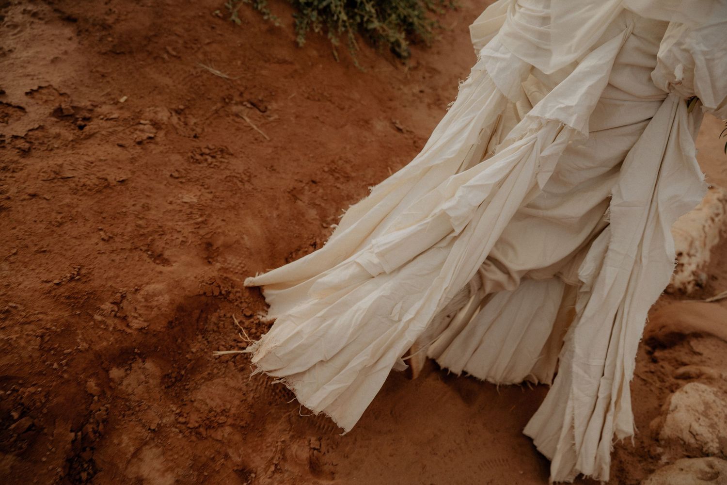 White fabric billows and swirls dramatically against rustic desert ground.