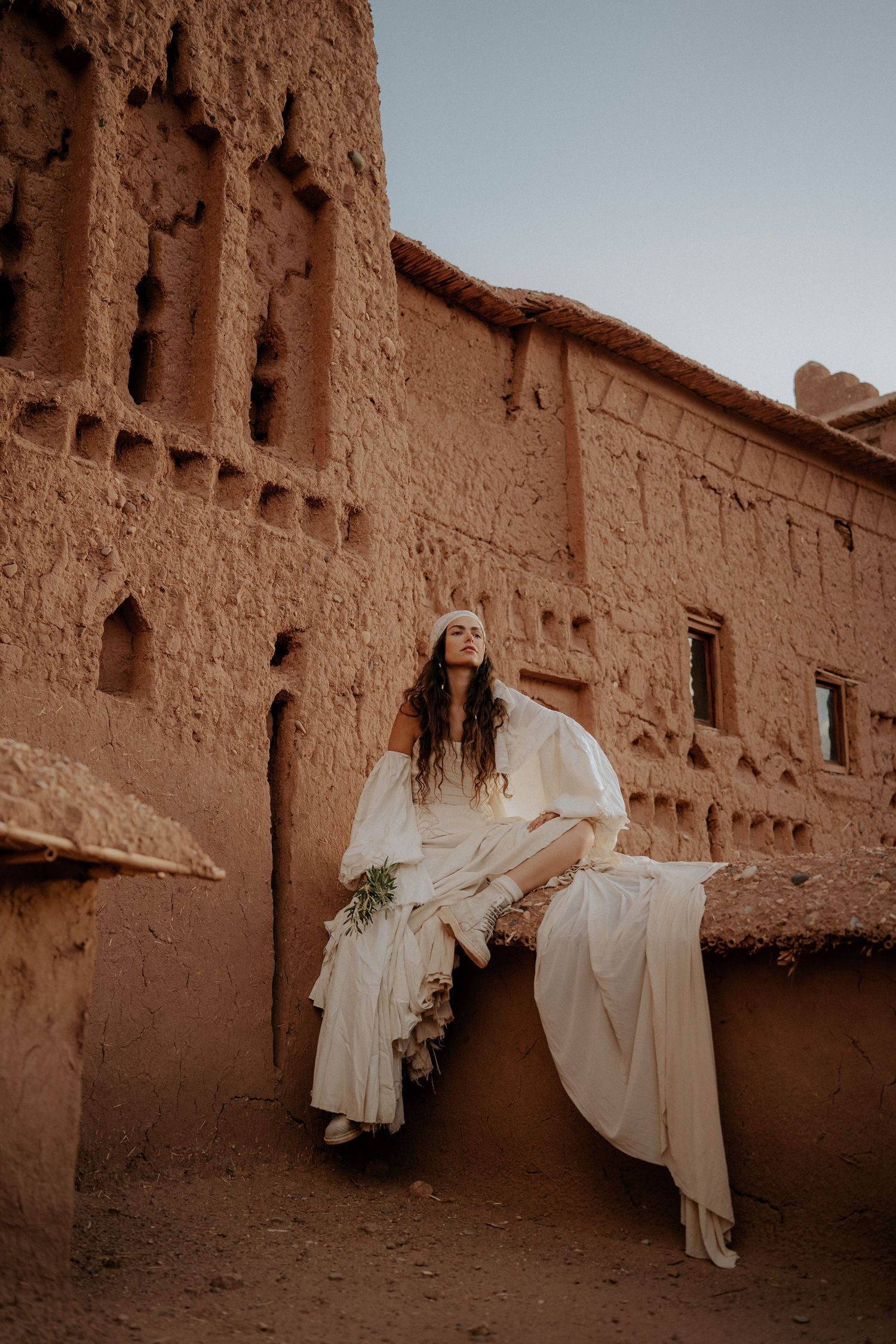 Ethereal white dress movement captured against traditional Moroccan clay architecture.