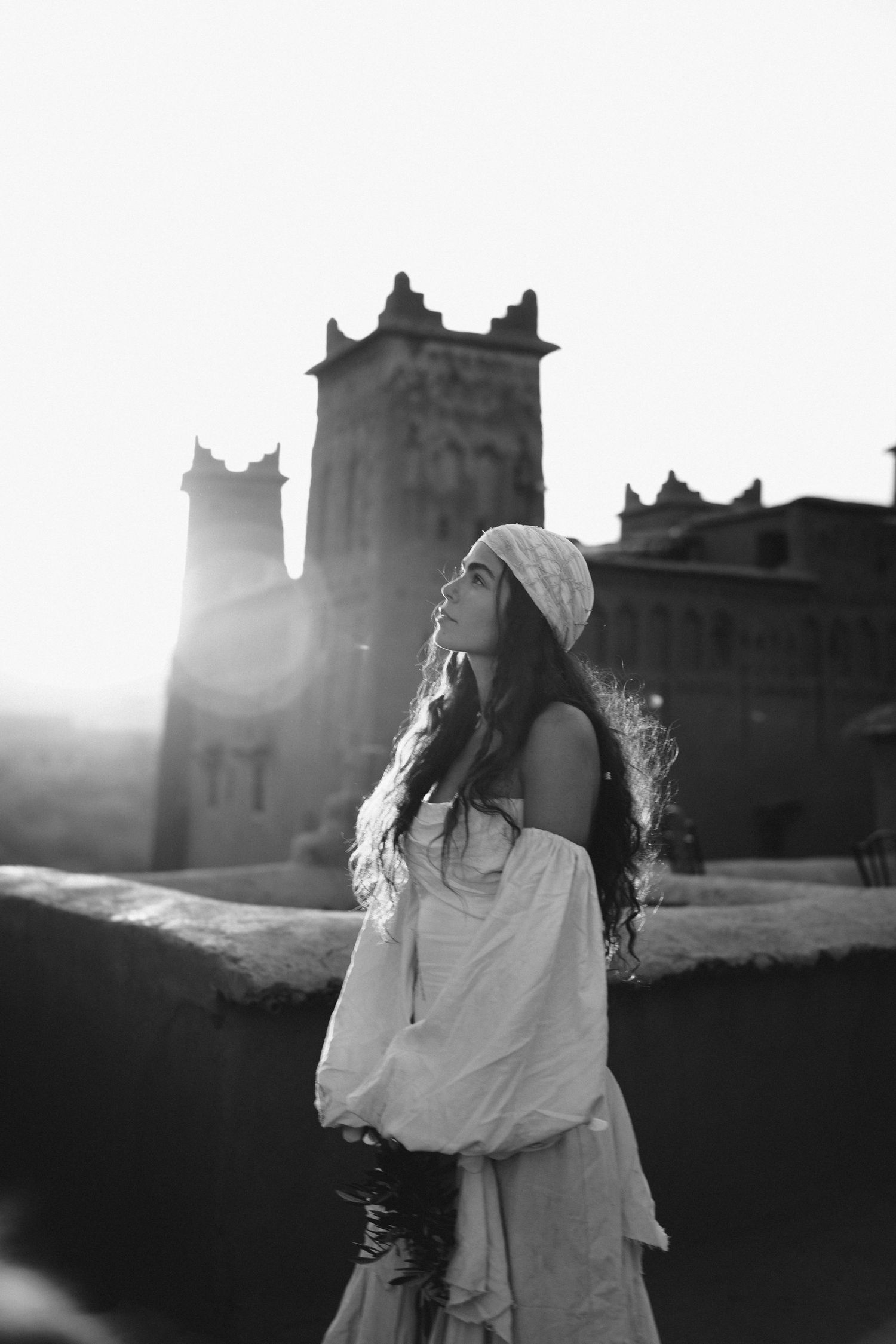 Black and white portrait with dramatic backlighting against historic desert architecture.