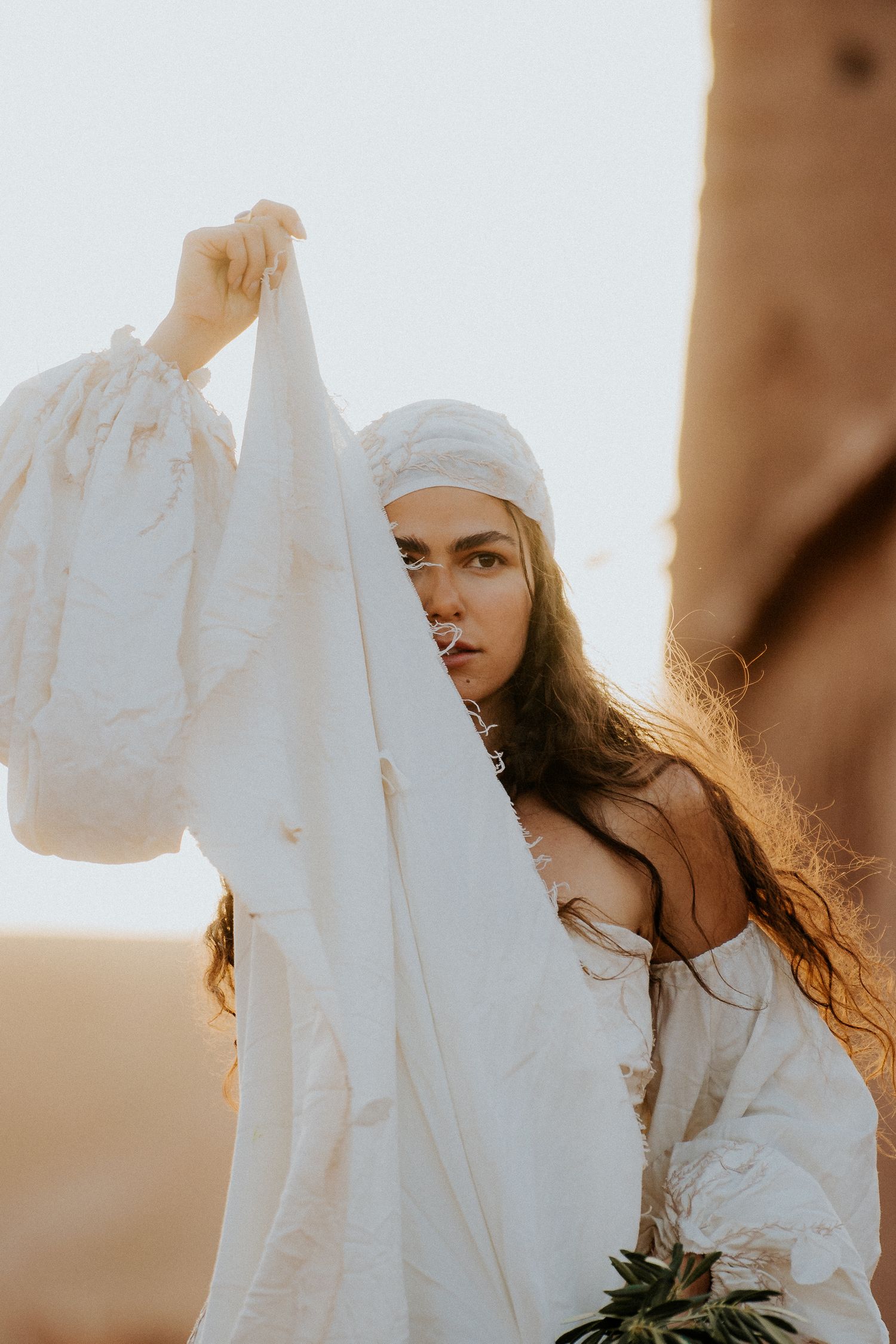 Artistic close-up of flowing white fabric movement against desert sky.