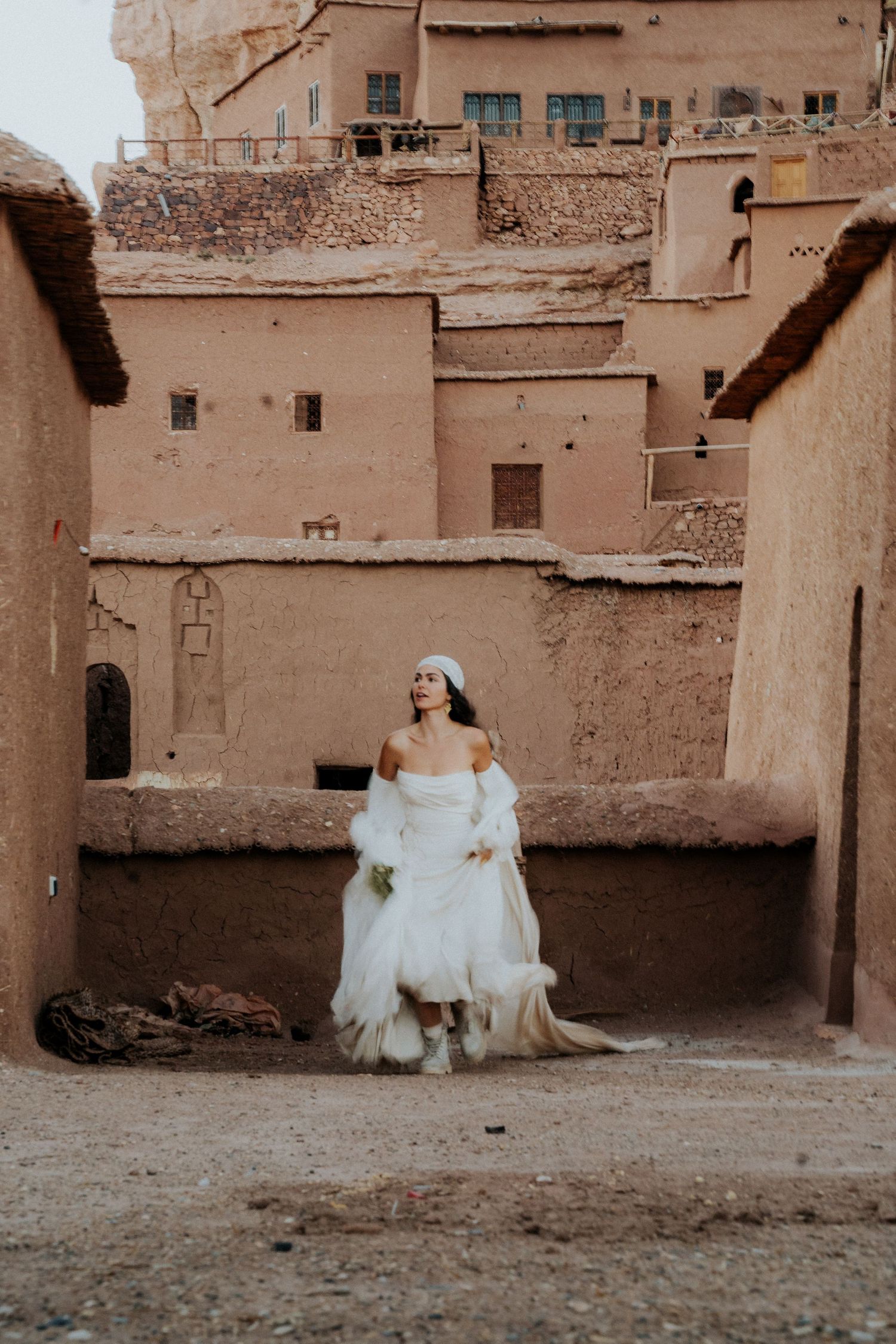 White wedding dress contrasts beautifully against traditional adobe buildings in Morocco.