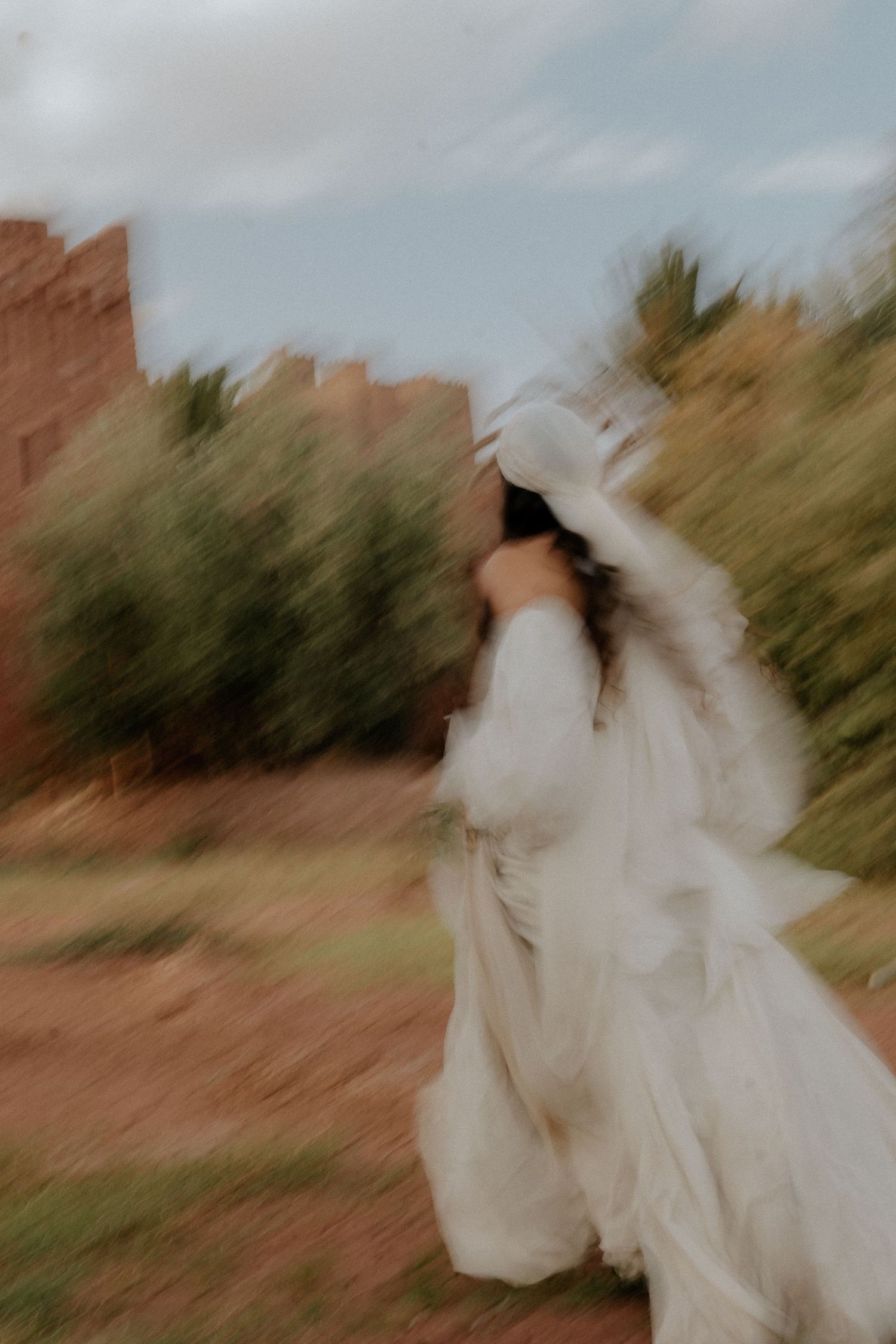 Motion-blurred photograph of flowing white fabric against desert landscape.