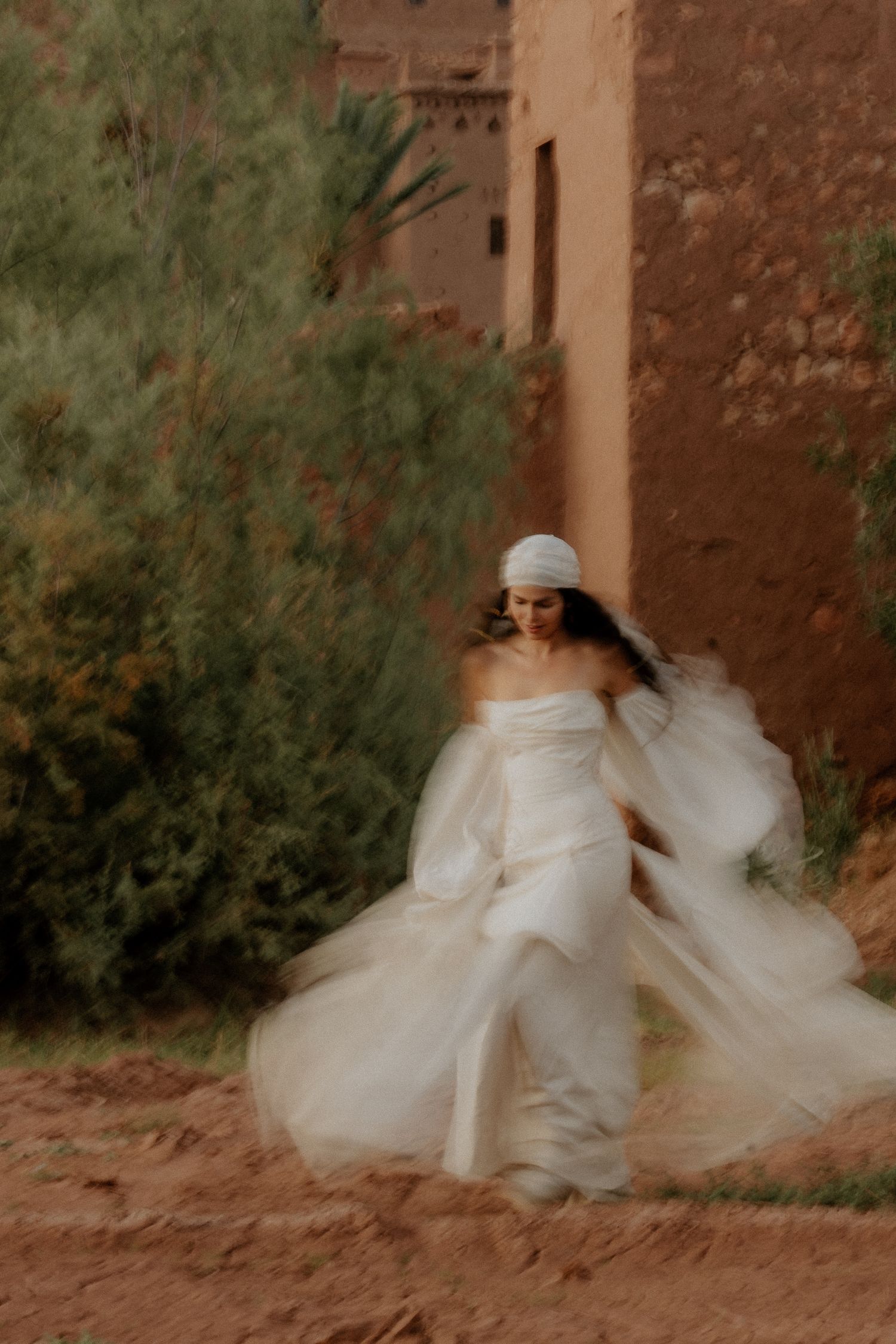 Ethereal dance movement captured with swirling white dress against adobe walls.