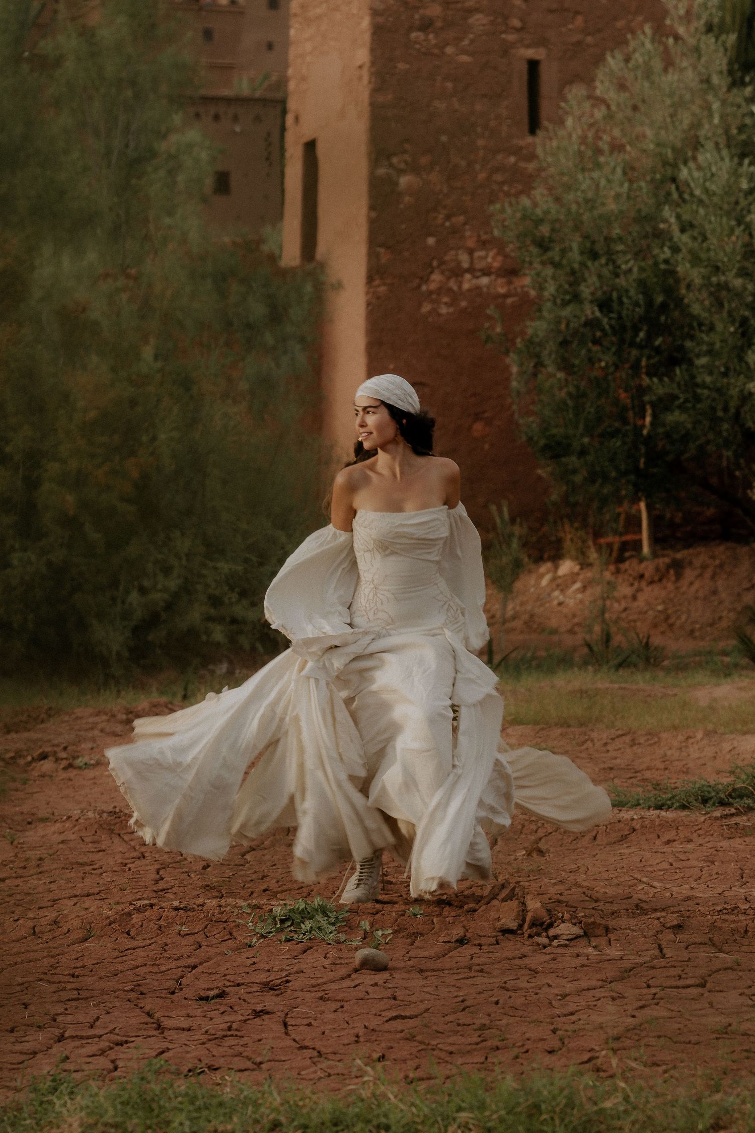 Dramatic spinning motion creates circular patterns with flowing white fabric against earthy backdrop.