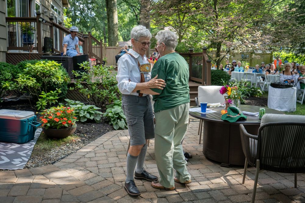 People enjoying a sunny outdoor gathering with food and drinks in a lush garden patio setting.