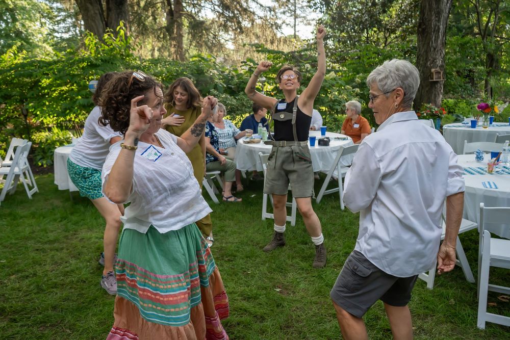 A group of people dancing together outdoors at a summer garden party.