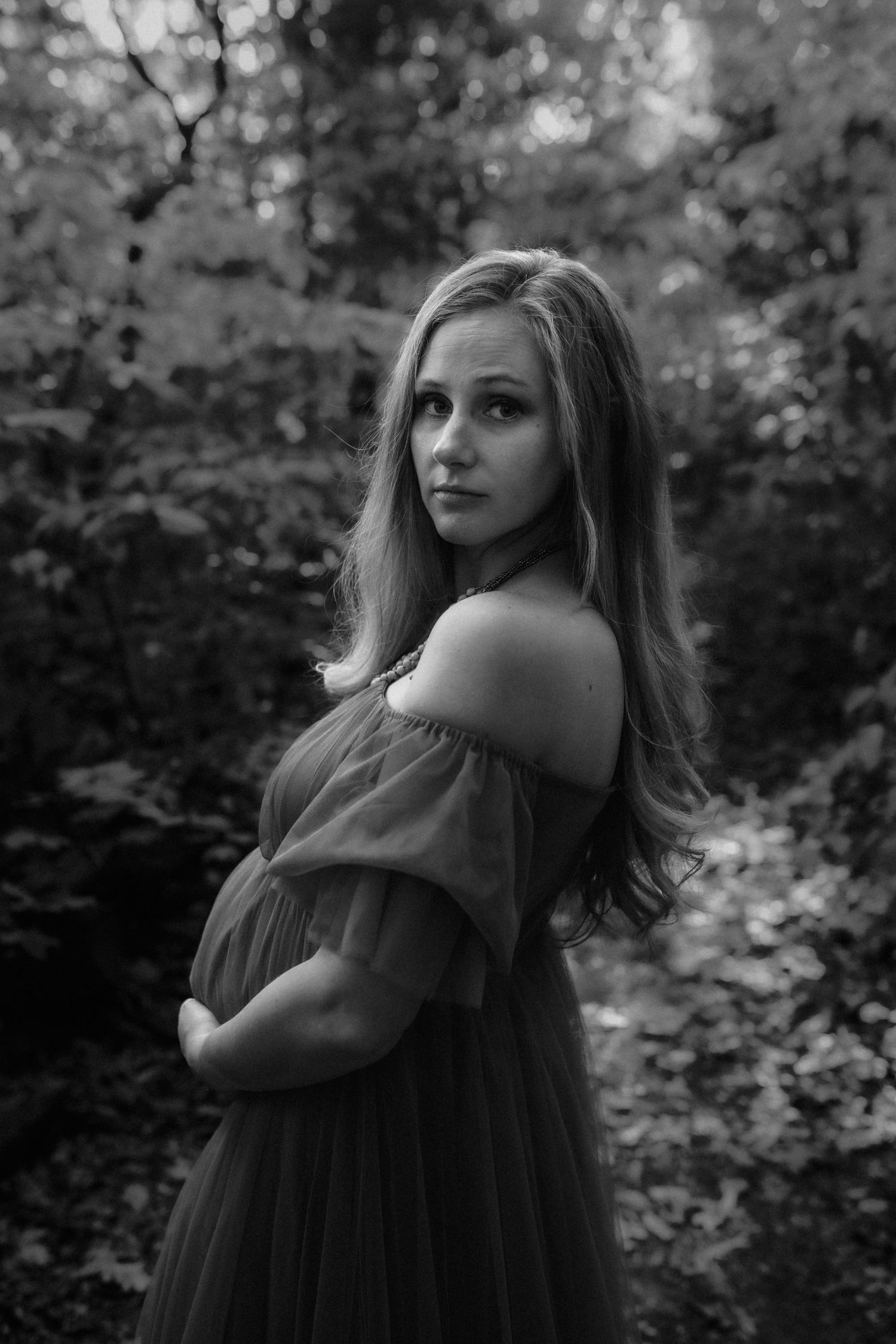 Artistic black and white portrait featuring flowing fabric in a forest setting.