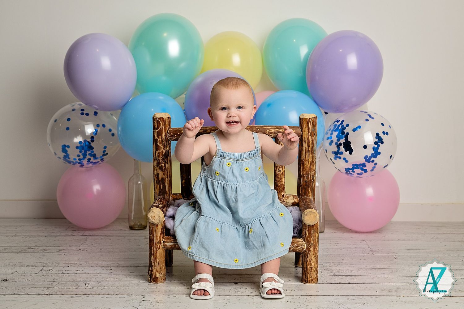 Colorful pastel balloon arch display with mint green, purple, and yellow balloons against a white backdrop.