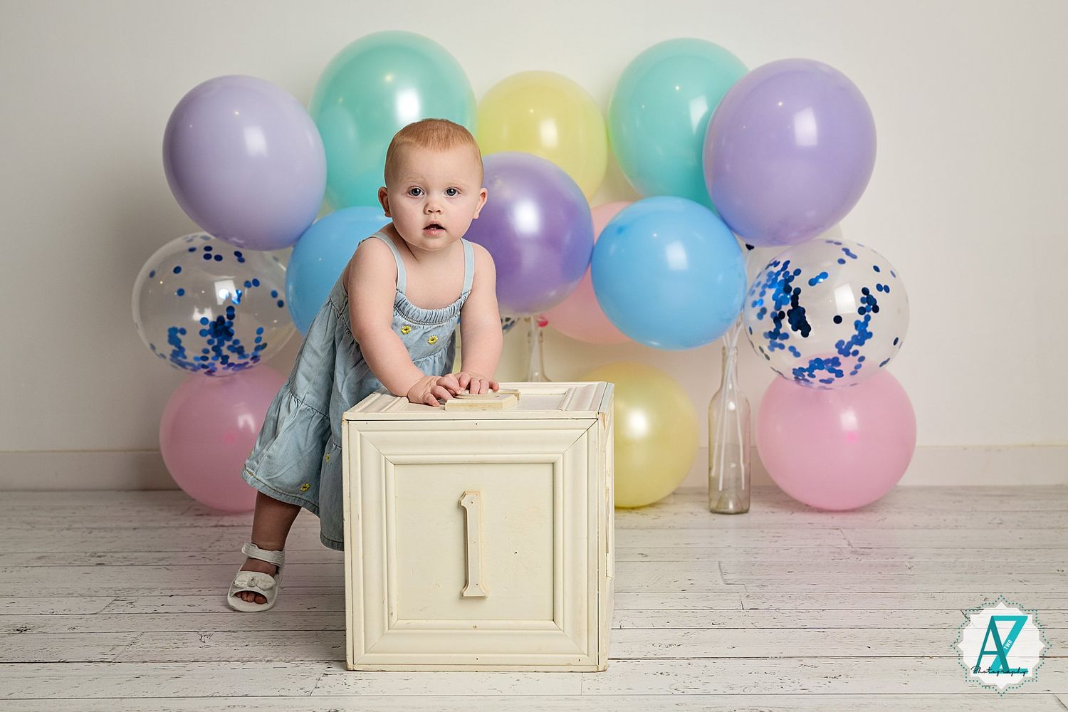 Birthday celebration setup with pastel balloons and a white vintage drawer against a light background.