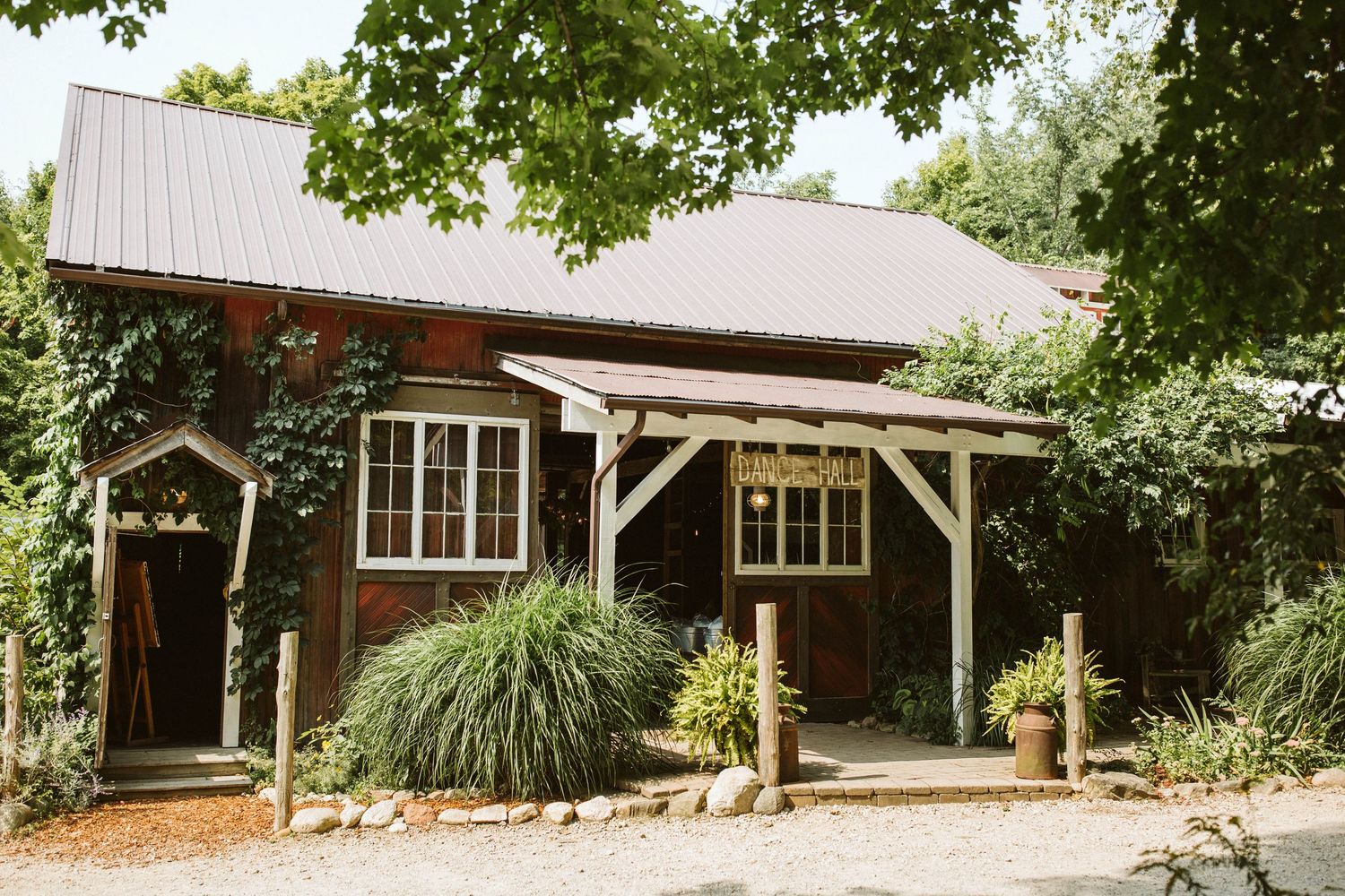 Rustic wooden event venue exterior with covered porch and landscaping.
