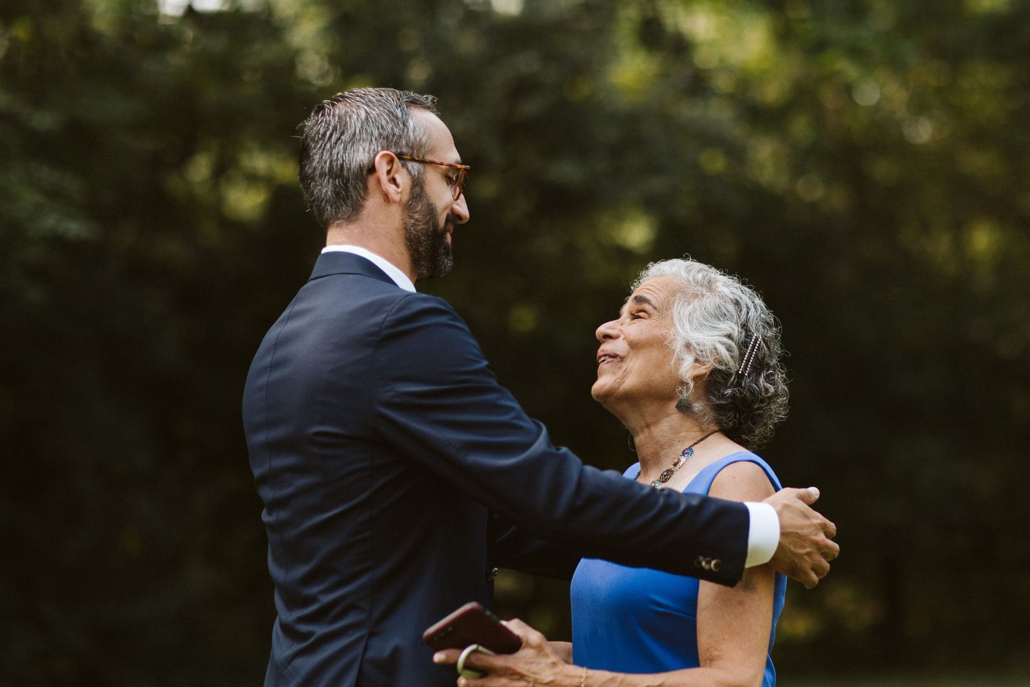 A couple shares a joyful first look moment in an outdoor garden setting.