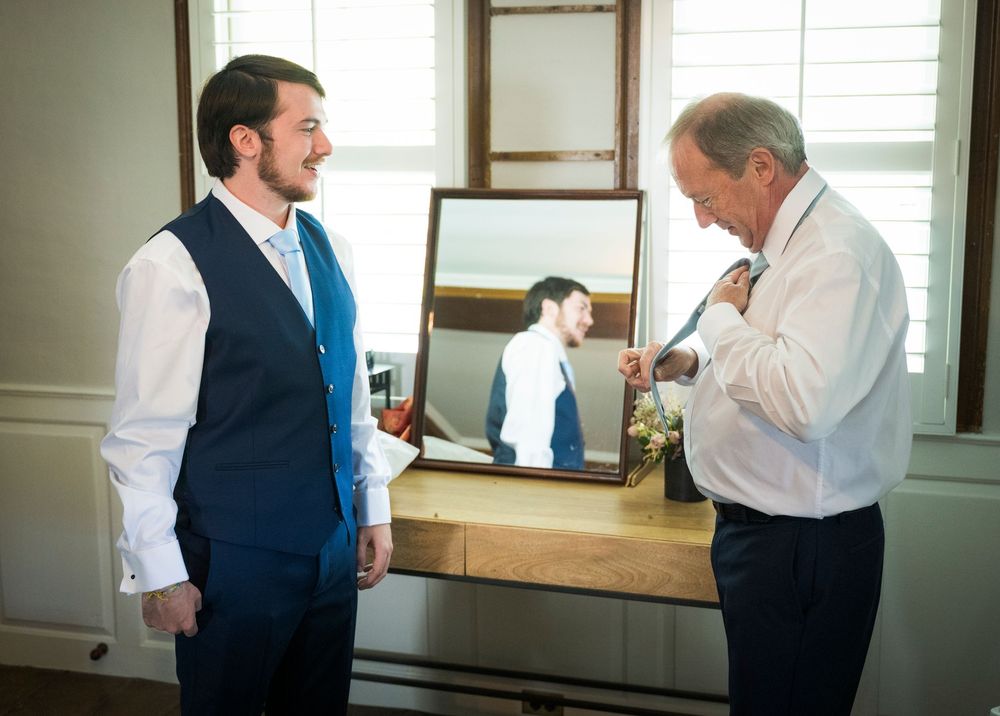 Wedding preparations in a bright indoor room with mirrors and natural lighting.