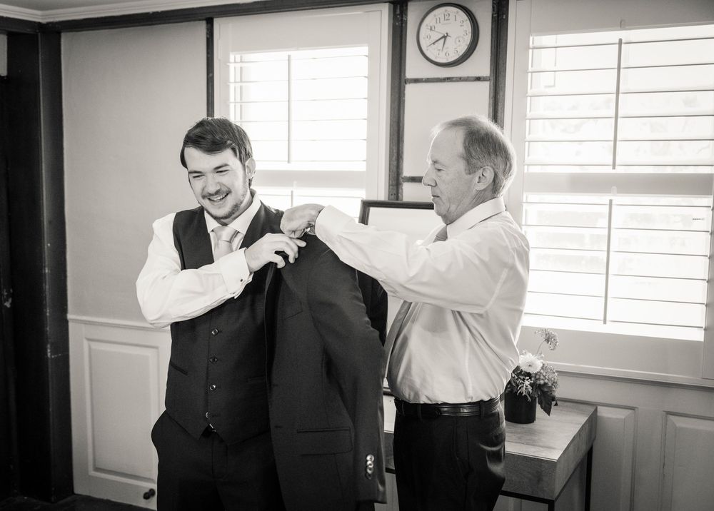 Black and white photo of wedding preparations in a bright interior room.
