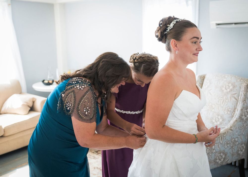 Wedding party getting ready in a bright room with white decor and elegant dresses.
